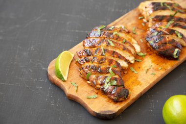 Siyah bir arka plan üzerinde rustik ahşap tahta üzerinde ızgara chipotle tavuk göğsü, yan görünüm. Kopyalama alanı.