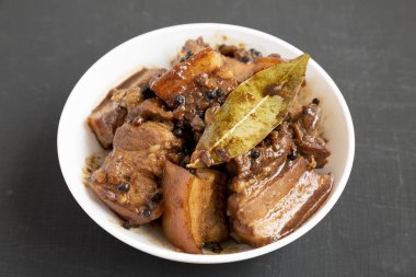 Siyah bir yüzey üzerinde beyaz bir kase içinde Ev yapımı Filipinli Adobo Domuz,