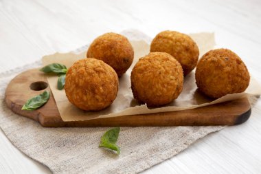 Beyaz ahşap yüzeyüzerinde fesleğen ile ev yapımı kızarmış Arancini, si