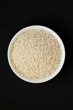 Organik Arborio pirinç siyah bir arka plan üzerinde beyaz bir kapta, üst 