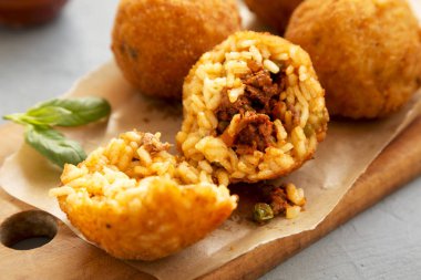 Bir rustik ahşap tahta üzerinde fesleğen ile ev yapımı kızarmış Arancini, sid