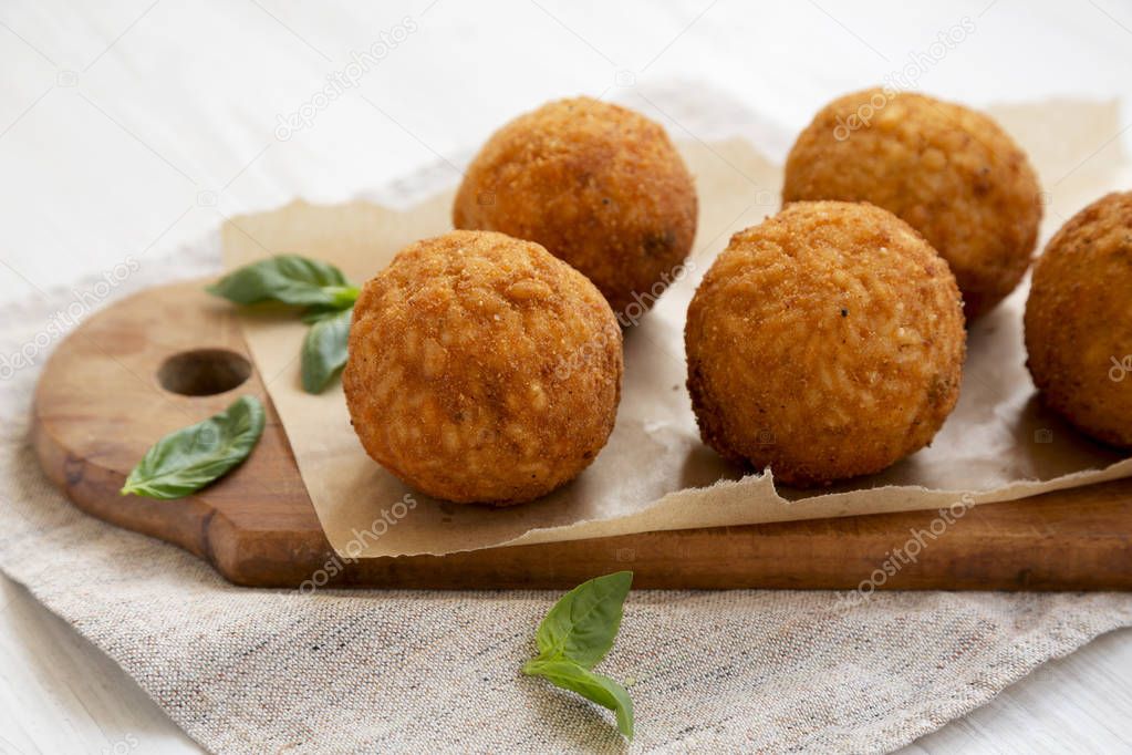 Homemade fried Arancini with basil on a white wooden background,