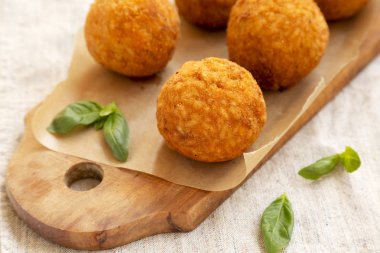 Rustik ahşap tahta üzerinde fesleğen ile ev yapımı kızarmış Arancini, yan görünüm. İtalyan pirinç topları. Close.