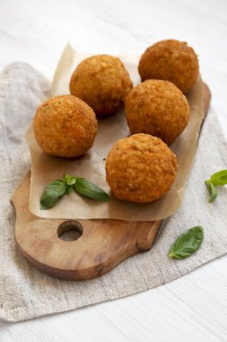 Bir rustik ahşap tahta üzerinde fesleğen ile ev yapımı kızarmış Arancini, düşük