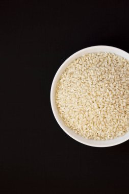 Organik Arborio pirinç siyah bir yüzeyüzerinde beyaz bir kapta, üst vie