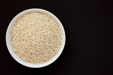 Organik Arborio pirinç siyah bir arka plan üzerinde beyaz bir kapta, üst 