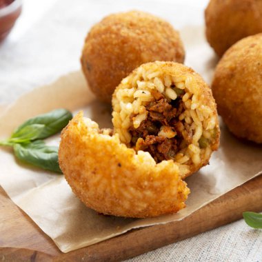 Bir rustik ahşap tahta üzerinde fesleğen ile ev yapımı kızarmış Arancini, sid