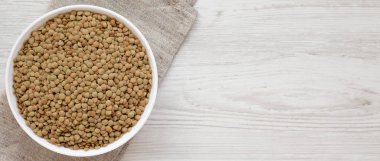 Beyaz ahşap yüzey üzerinde beyaz bir kapta organik yeşil mercimek,