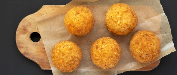 Siyah bir sırt üzerinde rustik ahşap tahta üzerinde ev yapımı kızarmış Arancini