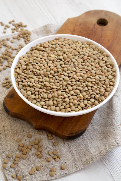 Rustik ahşap bir tahta üzerinde beyaz bir kapta Organik yeşil mercimek, 