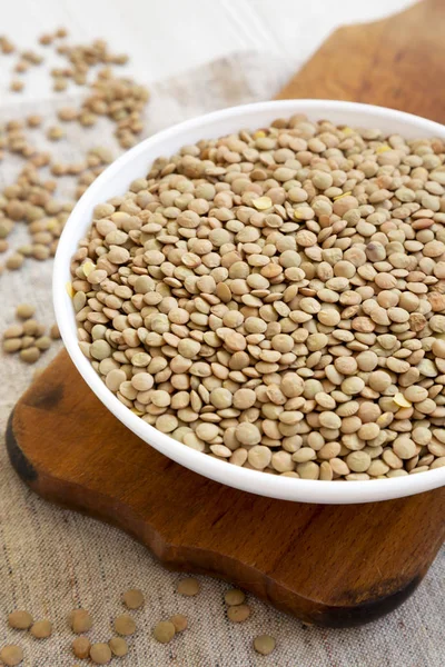 Rustik ahşap bir tahta üzerinde beyaz bir kapta Organik yeşil mercimek, 