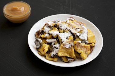 Siyah bir yüzeyüzerinde ev yapımı Alman Kaiserschmarrn gözleme, yan 