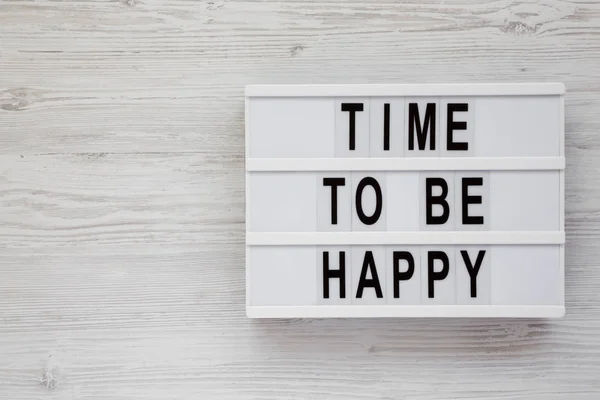 "Ώρα να είσαι ευτυχισμένος" λέξεις σε ένα φωτεινό κουτί σε μια λευκή ξύλινη επιφάνεια — Φωτογραφία Αρχείου