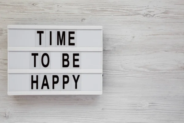 'Hora de ser feliz' palavras em uma caixa de luz em um backgro de madeira branca — Fotografia de Stock