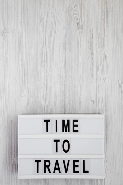 "Zeit zu reisen" steht auf einem Leuchtkasten auf weißem Holzuntergrund — Stockfoto