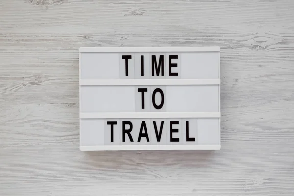 "Zeit zu reisen" steht auf einem modernen Brett auf einem weißen Holztisch. — Stockfoto