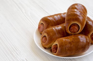 Beyaz bir ahşap üzerinde beyaz bir tabak üzerinde ev yapımı sığır sosis kolache