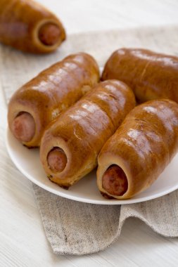 Siyah bir backgr üzerinde beyaz bir tabak üzerinde ev yapımı sığır sosis kolache