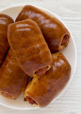 Beyaz bir ahşap üzerinde beyaz bir tabak üzerinde ev yapımı sığır sosis kolache