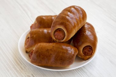 Beyaz bir ahşap üzerinde beyaz bir tabak üzerinde ev yapımı sığır sosis kolache