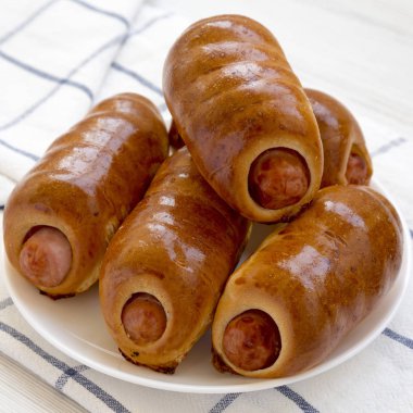 Beyaz bir ahşap üzerinde beyaz bir tabak üzerinde ev yapımı sığır sosis kolache