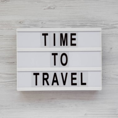 'Time to travel' words on a lightbox on a white wooden backgroun