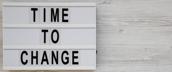 'Time to change' words on a modern board on a white wooden background, top view. Overhead, from above. Flat lay. Copy space.