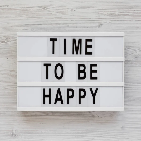 "Время быть счастливым" слова на светящейся коробке на белом деревянном бэкгро — стоковое фото