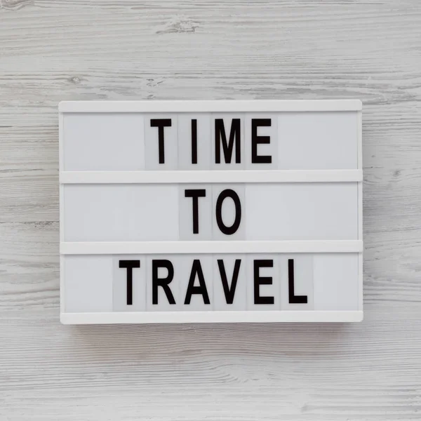 "Час подорожувати" слова на лайтбоксі на білому дерев'яному фоні — стокове фото