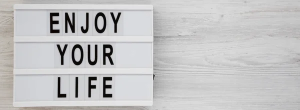 'Enjoy your life' words on a modern board over white wooden back — Stock Photo, Image