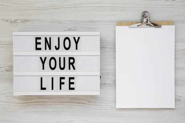 'Disfruta de tu vida' palabras en una caja de luz sobre fondo de madera blanca — Foto de Stock