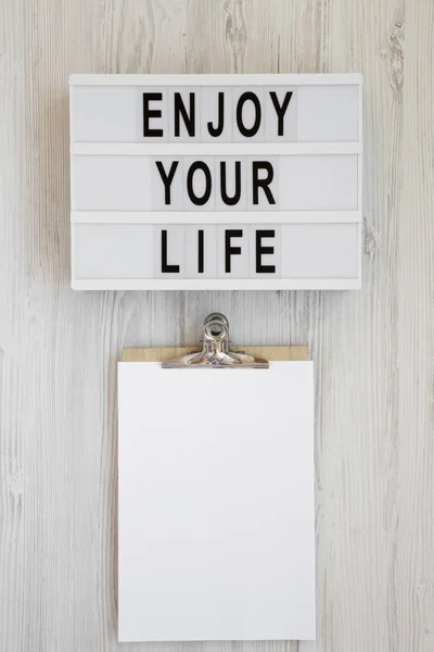Lightbox with text 'Enjoy your life', noticepad with blank sheet — Stock Photo, Image
