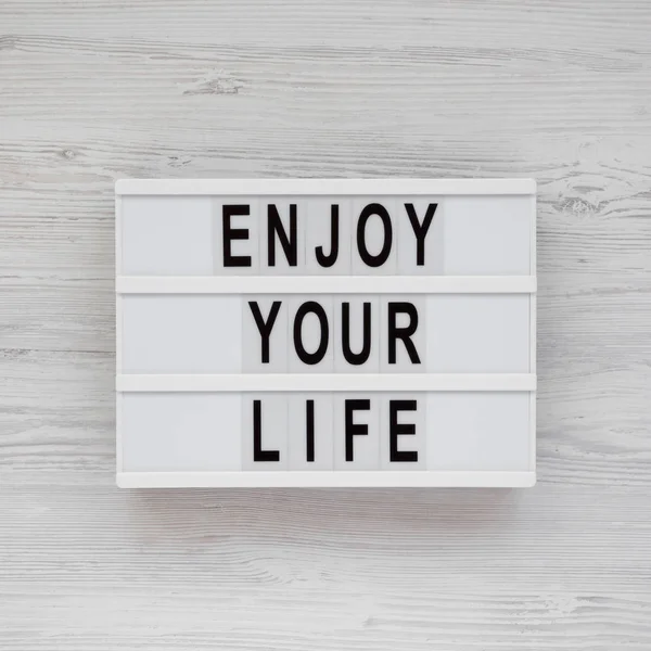 'Enjoy your life' words on a modern board over white wooden surf — Stock Photo, Image