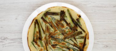 Bir wh üzerinde beyaz bir tabak üzerinde ev yapımı Kore Pajeon scallion gözleme