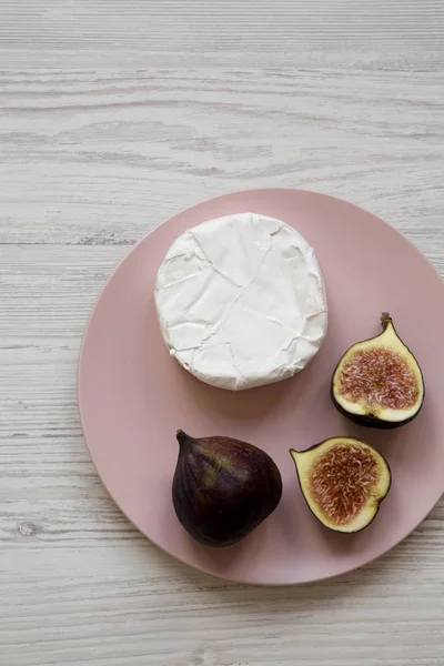 Camembert veya beyaz ahşap su üzerinde pembe bir tabak üzerinde incir ile brie — Stok fotoğraf