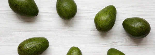 Whole avocados on a white wooden surface, top view. Overhead, fr — Stock Photo, Image