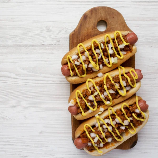 Homemade detroit style chili dog on a rustic wooden board on a w