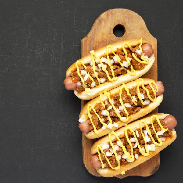 Homemade Detroit style chili dog on a rustic wooden board on a b