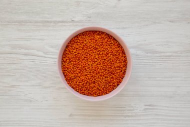 Beyaz ahşap arka planda pembe bir kasede kırmızı mercimek.