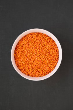 Siyah bir yüzey üzerinde pembe bir kasede kırmızı mercimek, üst manzara. Düz la