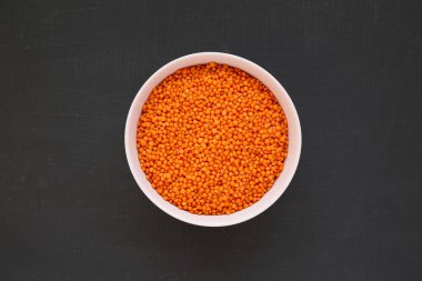 Siyah arka planda pembe bir kasede kırmızı mercimek, üst manzara. Düz