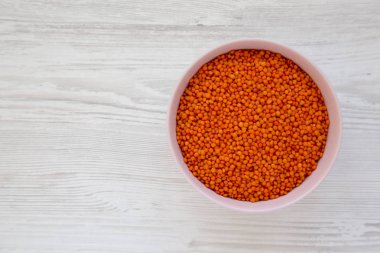 Beyaz ahşap arka planda pembe bir kasede kırmızı mercimek.