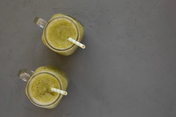 Zelfgemaakte groene komkommer appel smoothie in glazen potten op een grijze s — Stockfoto