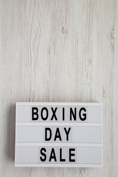 'Boxing day sale' words on a lightbox on a white wooden surface, top view. Overhead, from above, flat lay. Copy space.