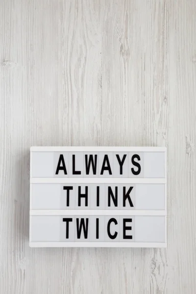 Réfléchissez toujours à deux mots sur une lightbox sur un fond en bois blanc — Photo