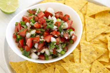 Beyaz ahşap üzerinde glütensiz tortilla cipsli Pico de Gallo. 