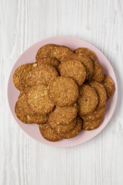 Beyaz ahşap arka planda pembe bir tabakta mısır gevreği kurabiyesi.