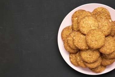 Üst manzara, siyah bir yüzey üzerinde pembe bir tabakta mısır gevreği. Fla