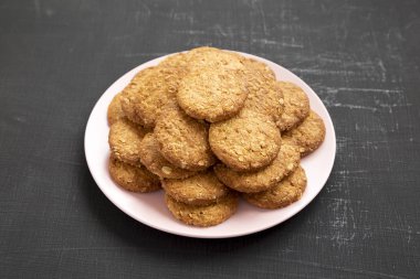 Siyah bir yüzey üzerinde pembe bir tabakta mısır gevreği kurabiyesi, yan görüş. CI