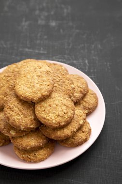 Siyah bir yüzey üzerinde pembe bir tabakta mısır gevreği kurabiyesi, yan görüş. Birlikte